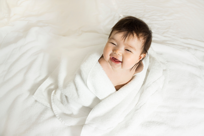 A happy five-month-old mixed race (Japanese - Caucasian) baby girl, being dried after a bath with towels