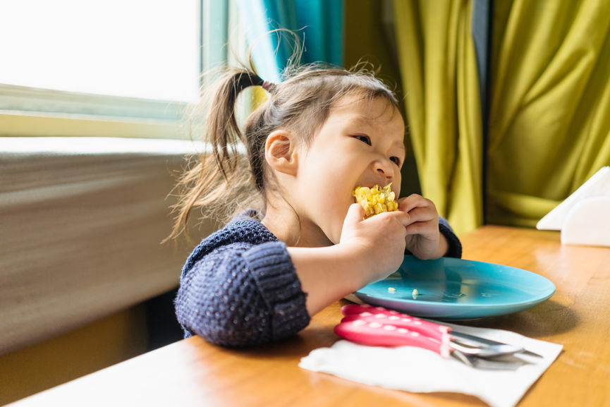 Toddler Girl Sitting In Restaurant And Eating