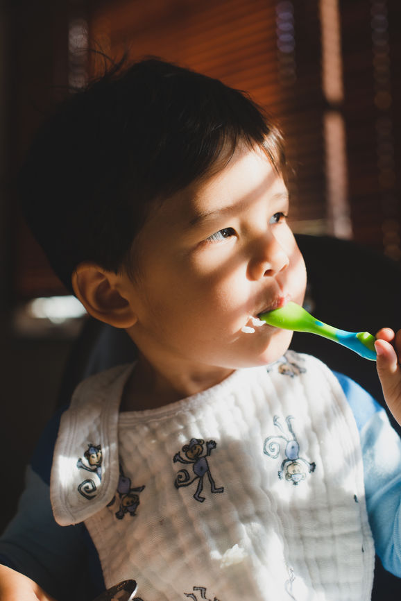 Little Kid Eating With A Spoon