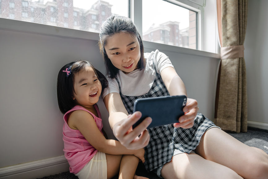 Adorable Girl And Her Mother Taking Selfie At Home