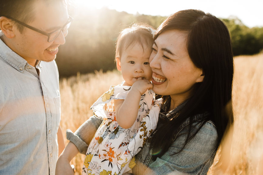 Happy Asian Family Snuggling, Cuddling And Being Playful Outdoors